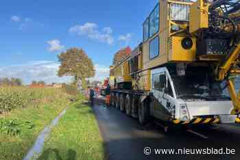Vrachtwagen met torenkraan kantelt in gracht langs Velveken