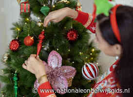 Basisschoolleerlingen versieren grote kerstboom vanuit een hoogwerker