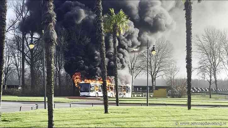 Biddinghuizen - Bus van Walibi Express in brand, zwarte rookwolken boven parkeerplaats attractiepark