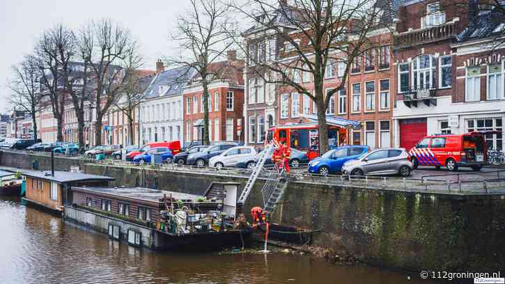 Woonboot maakt water aan het Lopendediep in Groningen, brandweer pompt boot leeg