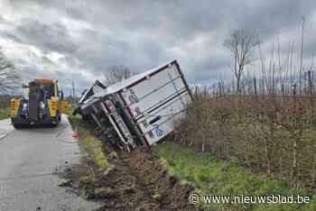 Vrachtwagen zakt weg in berm, ramt paal en kantelt