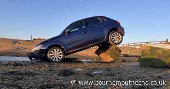 Car crashes into rock and gets wedged on top