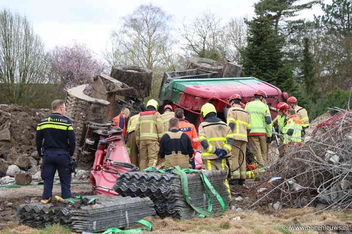 Persoon bekneld in cabine van gekantelde graafmachine