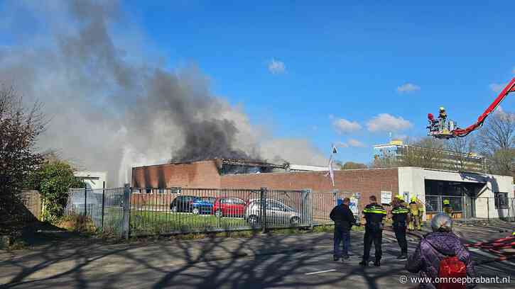 Grote brand in loods waar gesloopt wordt, rookwolken trekken over stad
