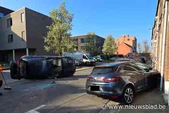 Auto over de kop na crash tegen geparkeerde wagen