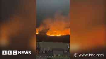 'Blaring' wildfire burns close to homes