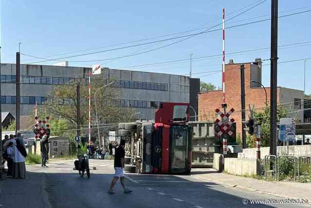 Vrachtwagen rukt bovenleiding af en kantelt op spooroverweg: grote hinder, twee treinen zonder airco staan stil