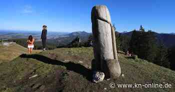 Maskierte stellen Holzpenis vor Bürogebäude auf