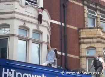 Terrifying moment child clings to window ledge above London high street shop before dramatic rescue