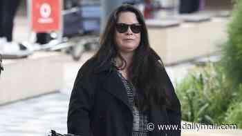 Iconic Charmed star Holly Marie Combs blends in with the locals as she arrives in Sydney for Supanova dressed down in a black trench coat