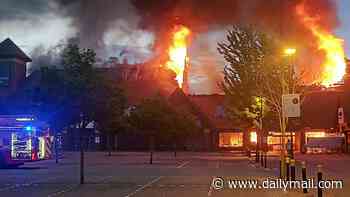 Massive blaze rips through shopping centre as roof collapses and residents are told to keep their windows shut
