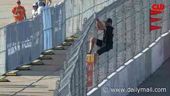 Terrifying moment NASCAR fan risks life by hopping fence to talk to driver on the track... before being arrested by federal agents
