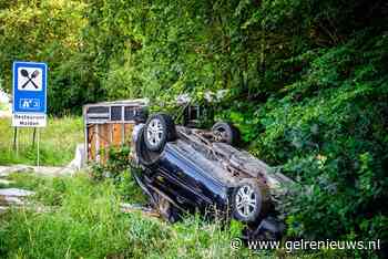 Auto met aanhanger ondersteboven in berm na crash