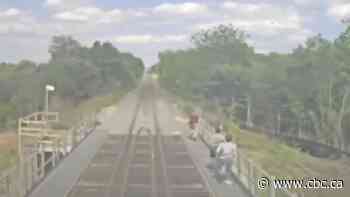 Video shows 3 people running on bridge beside Kitchener GO train as crew initiates emergency brakes
