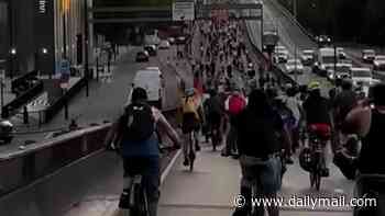 Reckless cyclists pull wheelies on illegal e-bikes and climb gantries after trespassing on dual carriageway for anti-car protest during roadworks