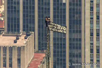 Two People Scale Empire State Building to Fly Peace Banner and Kiss