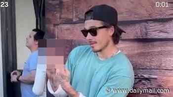 Brooklyn Beckham gives a two-finger salute as he admits wife Nicola Peltz isn't a fan of his fashion while sporting £715 Balenciaga boots and 'caretaker' keys
