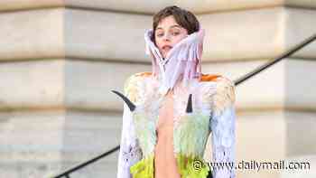 Emma Corrin goes braless in a bold and bright feathered jacket as they lead the star arrivals at the Schiaparelli Haute Couture show in Paris