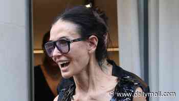 Demi Moore looks animated as she carries a £3,400 handbag while leaving the Balenciaga showroom in Paris after a fitting