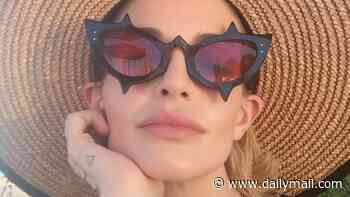 Kelly Osbourne poses in a sheer dress and big straw hat as she relaxes on holiday after getting 'back to her best' following body-shaming row