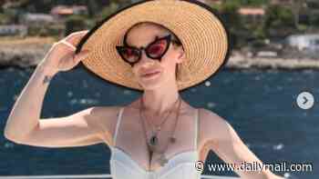 Kelly Osbourne wows in plunging white swimsuit and straw hat as she continues sharing glamorous holiday snaps after getting 'back to her best' following body-shaming row