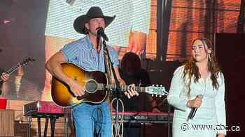 Dene woman sings onstage with Riley Green at Country Thunder festival
