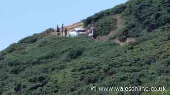 Car drives down narrow coastal walking path