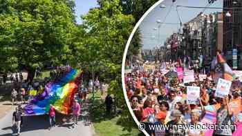Honderden mensen lopen met enorm regenboog spanddoek door Amsterdam tijdens Pride Walk