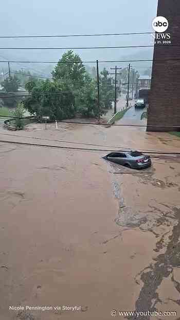 Shocking moment muddy floodwaters sweep car down street