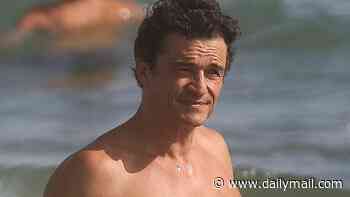 Orlando Bloom, 49, shows off his ripped physique in the beach shower as he puts on a cosy display with bikini-clad model girlfriend Luisa Laemmel, 28, at the beach in Italy