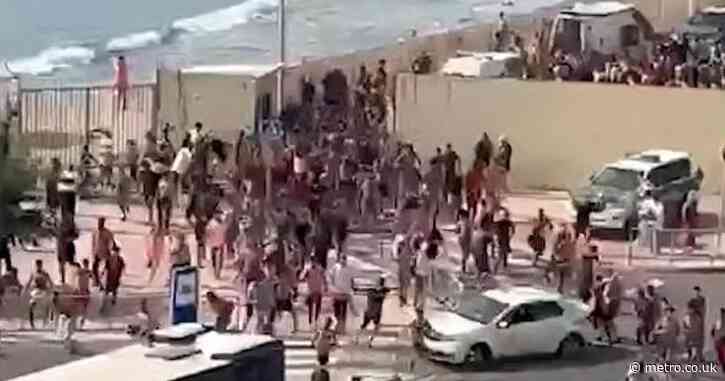 City pleads for national emergency after thousands of migrants swarm onto beach