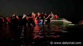 Moment packed small boat set for the UK gets caught on sandbank on a French beach... as police watch on