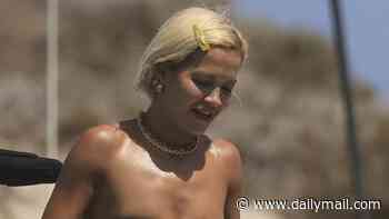 Rita Ora sizzles in a strapless black bikini as she enjoys a cigarette with her husband Taika Waititi during sun-soaked yacht day in Ibiza