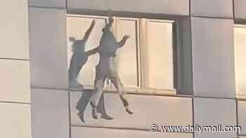 Hair-raising moment woman hangs from 11th floor of burning building before making daring jump to safety