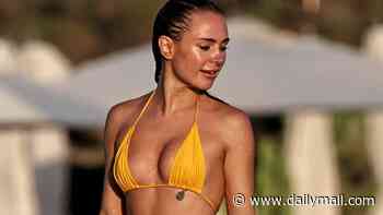 Kimberley Garner models a yellow bikini from her own collection as she hits the beach in Ibiza