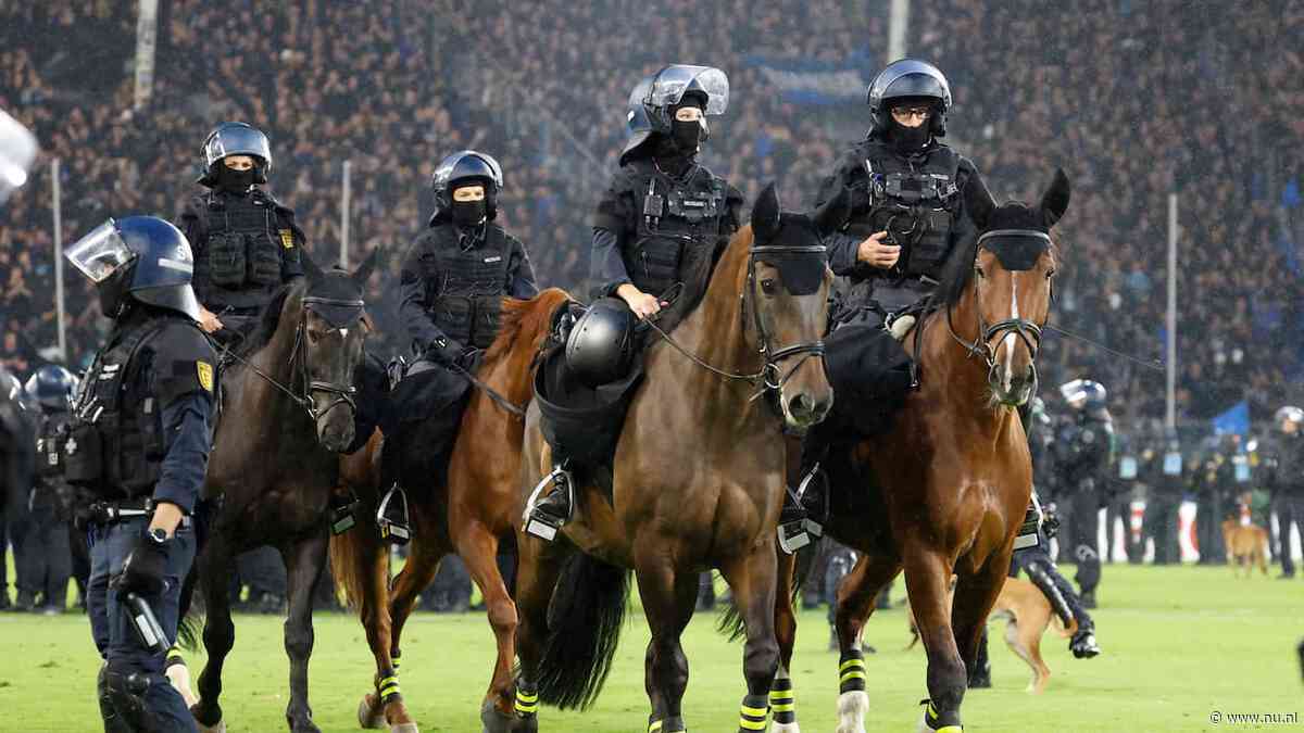 Politie met paarden op het veld bij rellen tijdens Duitse bekerwedstrijd