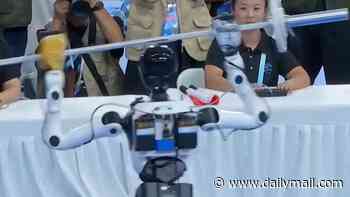 Moment weightlifting robot collapses onto judges' table during Olympics... before being rushed onto a stretcher