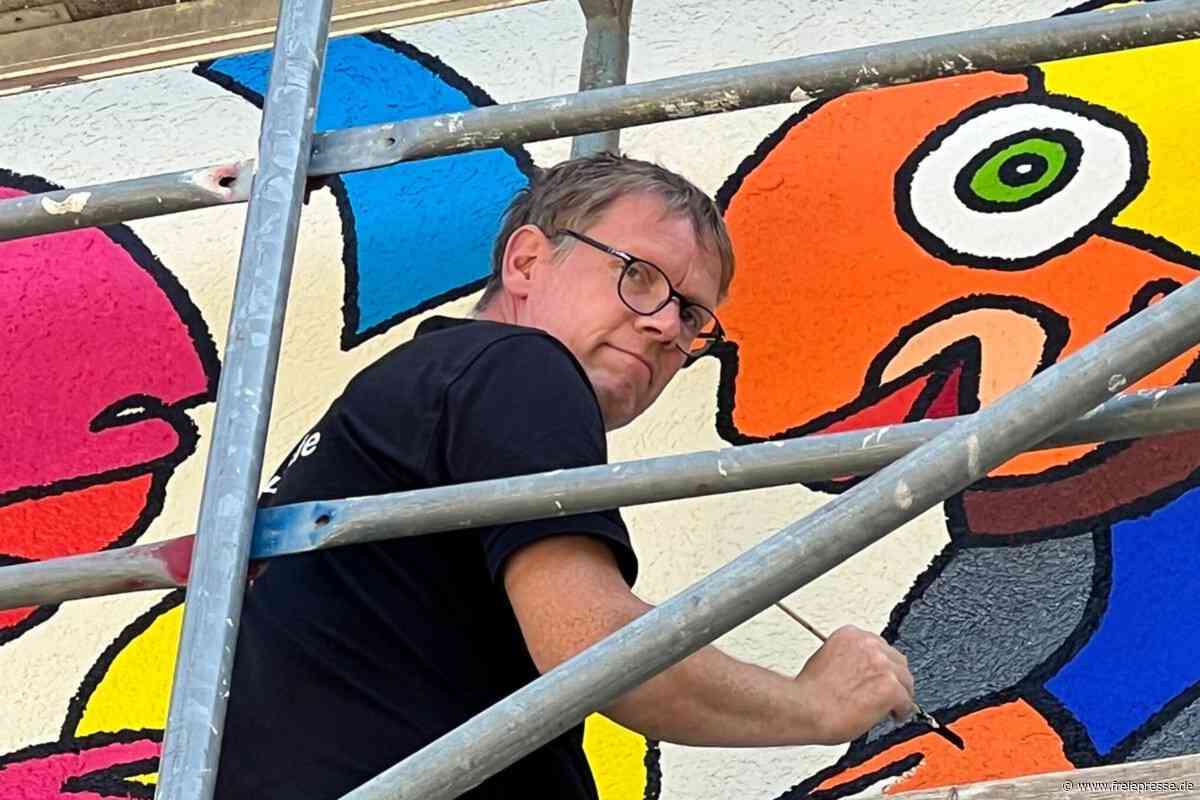 Er macht Auerbach bunter: Star-Künstler bemalt graues Kaufhaus im Vogtland mit Comic-Muppets