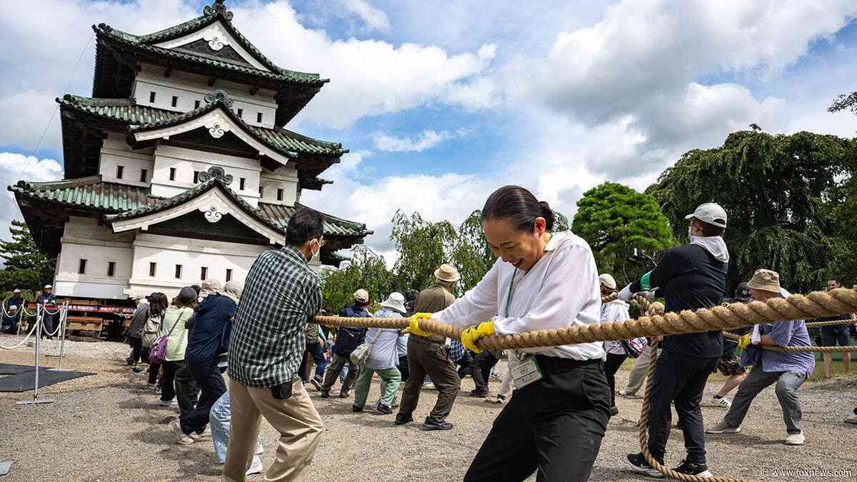 Hundreds of volunteers pull 360-tonne historic Japanese castle back into place by hand