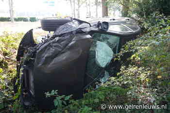 Auto op zijn kant in bosschages na botsing