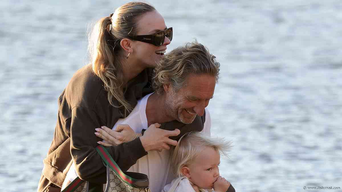 Precious cargo! Justin Hemmes, 54, carries partner Madeline and their one-year-old son Jaeger ashore after arriving home by seaplane