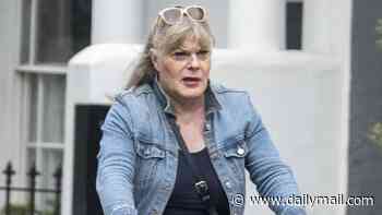 Suzy Eddie Izzard, 64, sports a pleated mini-skirt and towering knee-high boots as she cycles through Notting Hill without a helmet