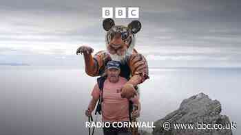 Why is this man walking while carrying a tiger?