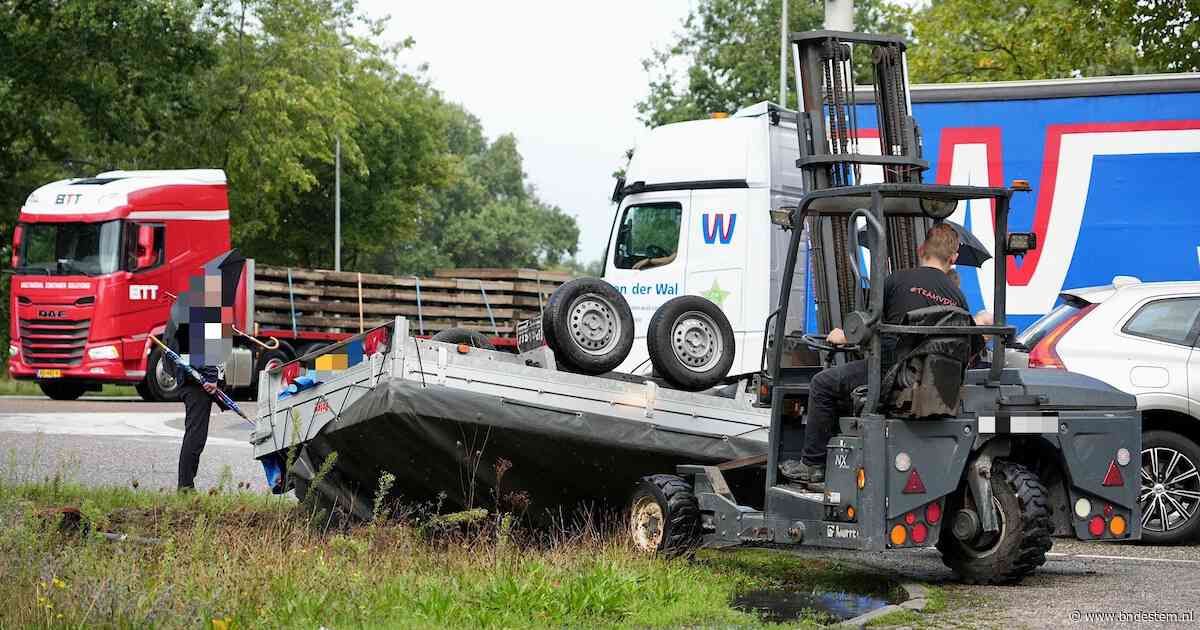 Aanhanger vliegt over de kop in Dongen, vrachtwagenchauffeur schiet te hulp