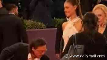 Brooklyn Beckham is Nicola Peltz's dutiful red carpet assistant once again as he rearranges the train of her gown at the Deauville Film Festival