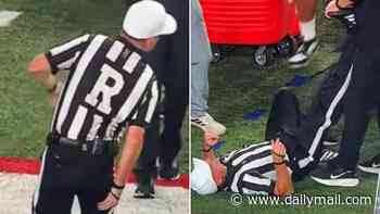 Moment college football referee is carted off with injury after writhing around in pain on sideline