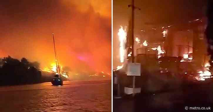Holidaymakers run into sea as they watch resort go up in flames