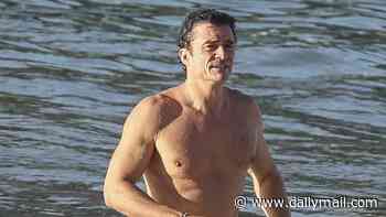Orlando Bloom, 49, shows off his ripped physique as he emerges from the sea after a swim in Spain