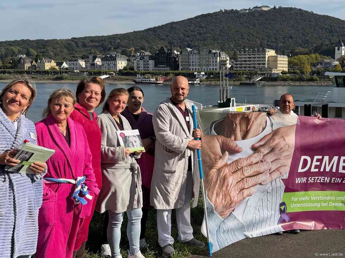 Pflegepersonal fährt im Bademantel über den Rhein