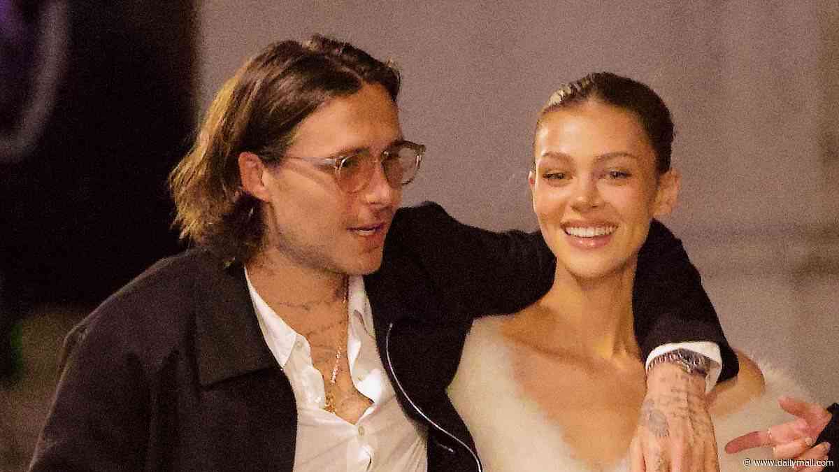 Brooklyn Beckham and ab-flashing Nicola Peltz pack on the PDA on a night out in Paris after snubbing his mum Victoria's show as the designer says she feels 'so blessed' to have the rest of her family supporting her